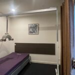 Rehabilitation bed setup in a small room with a ceiling-mounted traction device and purple mattress.