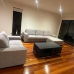 Modern living room with a gray sectional sofa, black coffee table, and warm hardwood floors.
