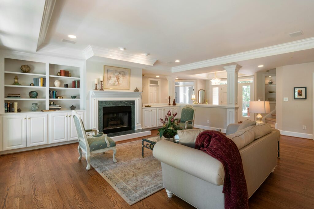 Bright living room with white built-in bookshelves, a marble-framed fireplace, and mint-green upholstered chairs.